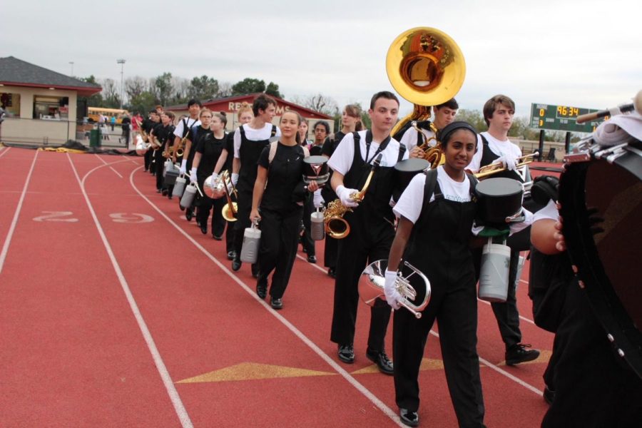The marching band walks in twos on their way to pre-game practice.
