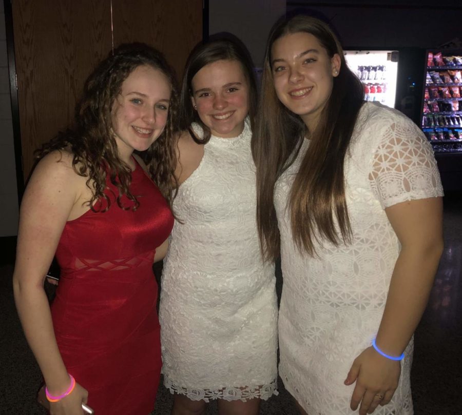 Serena Goodridge, Caroline Newman, and Paige Deal pose for a photo. Caroline and Paige wore white in spirit of the glow theme and to better reflect the use of black lights at the dance. 
