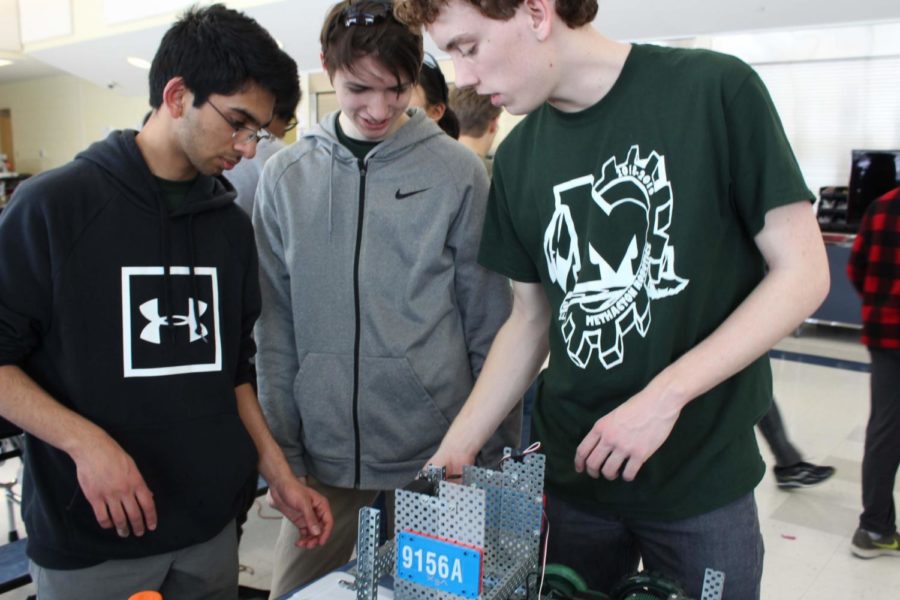 (from left) Senior Anurag Rao, Junior PJ Rossetti, and Senior Eli Smith discuss strategy and examine robot 9156A prior to the VEX competition on Feb. .
