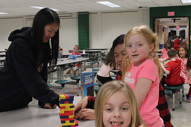 Club members and kids prepared to play Jenga in the cafeteria.