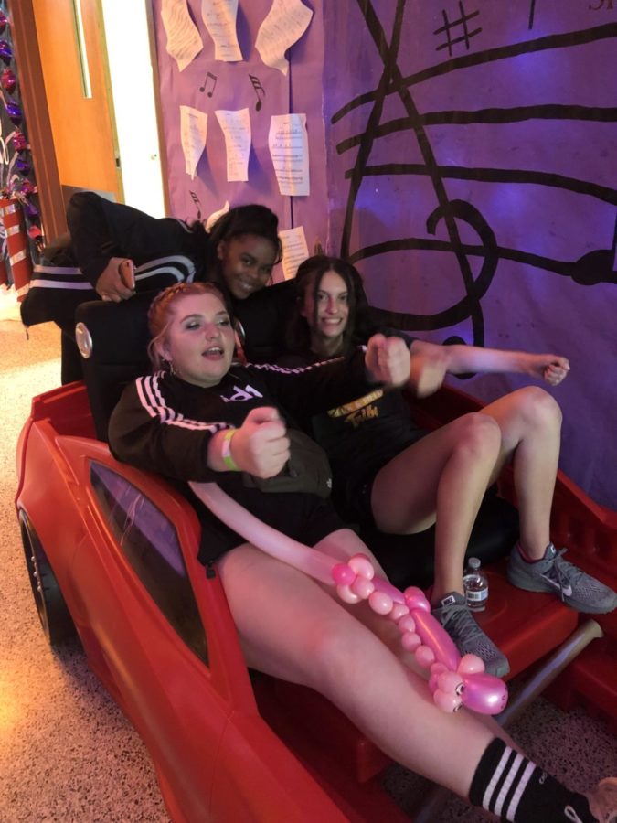 Katherine Mcgrath, Siani Ford-Barkley and Ellie Joseph act like they are driving a car in one of the many musically-themed hallways.