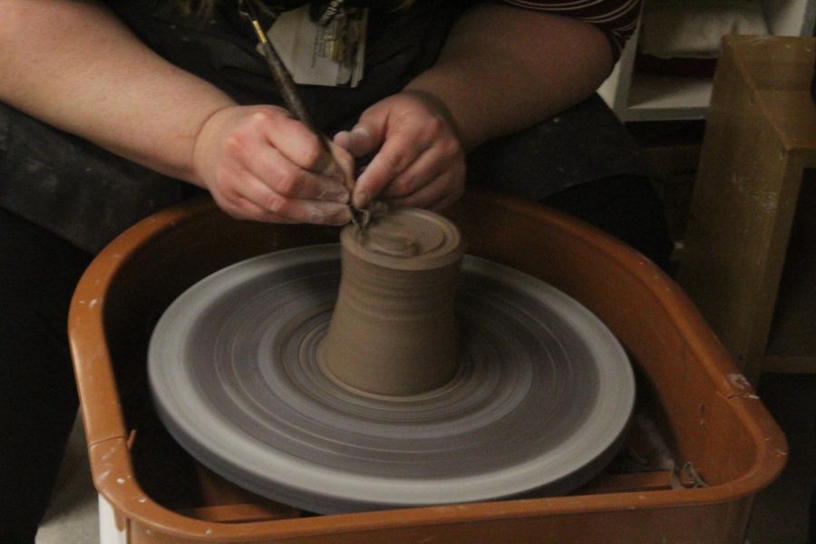Next, Ms. McCauly carves a ring into the base of the mug to protect it from surface damage. 

