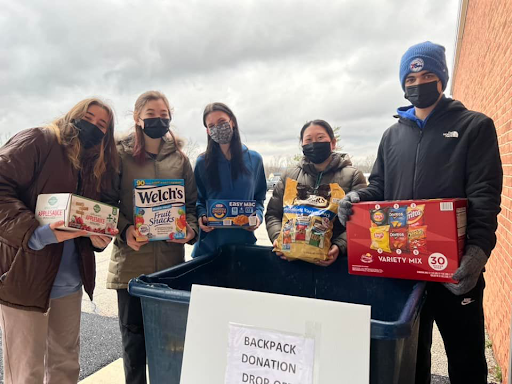 NHS members (from left) Brielle Anderson, Melanie Cohen, Lucy Kinghorn, and Jack Winters stand with Lianne Dacri (second from right), an NHS advisor and event coordinator, prior to loading donated food items that will benefit the district Backpack Program.
