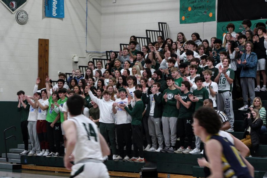 The Tribe, wearing green and white to celebrate the basketball team, cheer on the Warriors as they move back on defense. 