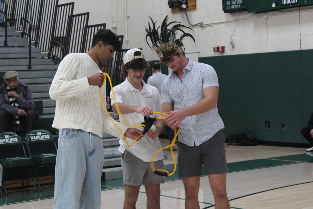 (from left) Seniors Dhruv Naik, Matt Decker and Tommy Kratz set up the slingshot to launch a shirt into the student section.
