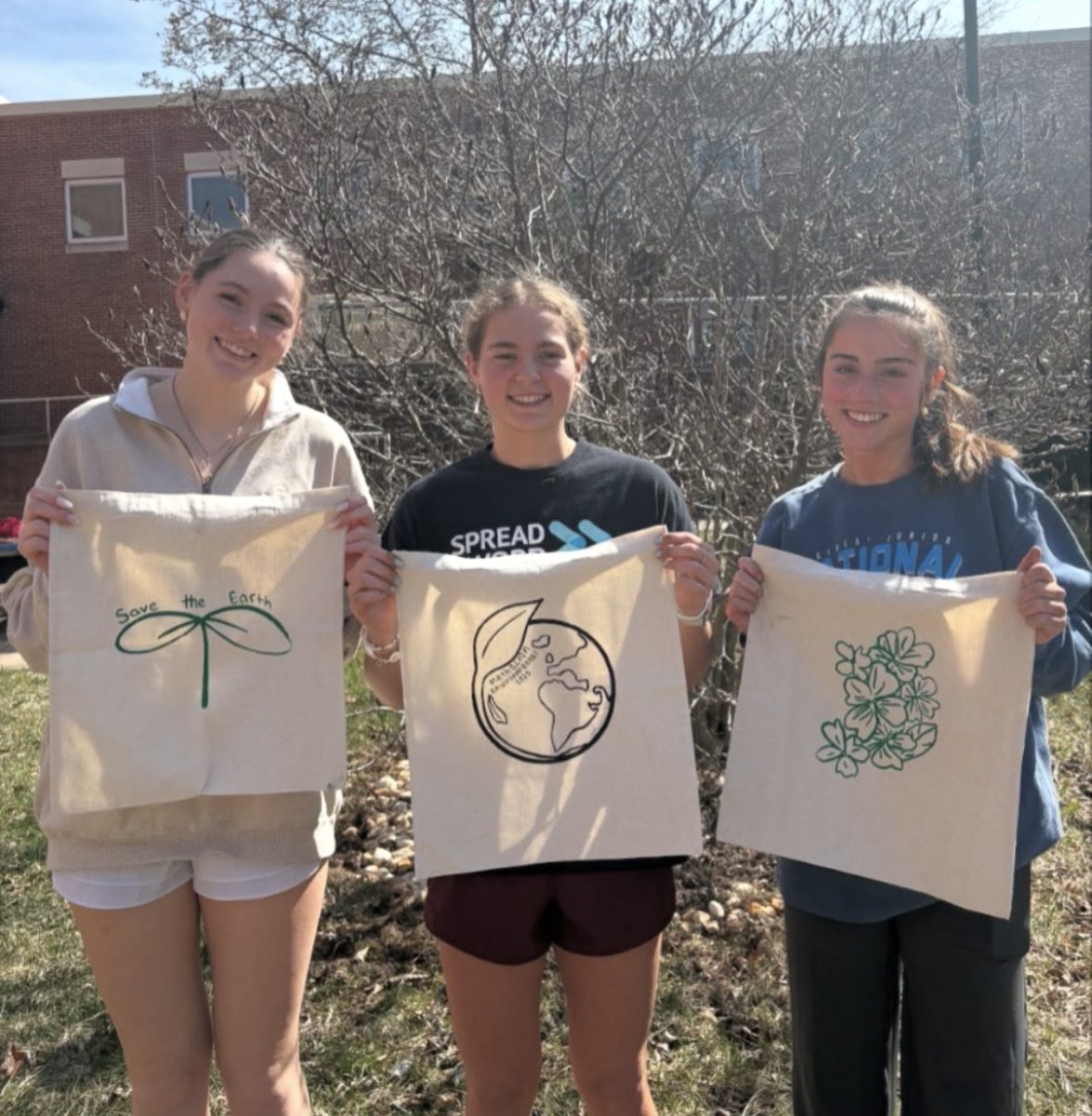(from left) Club member Emily Taylor and Environmental Club Presidents Arden Hartranft and Ceci Rehak hold totes with their screen print designs on Earth Day during the 2024-2025 school year. The club will host its annual thrift store on April 22 in the library.